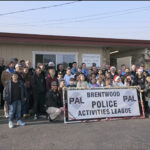 Officers from Brentwood Pal taking a group picture with kids during their Shop with a Cop event.