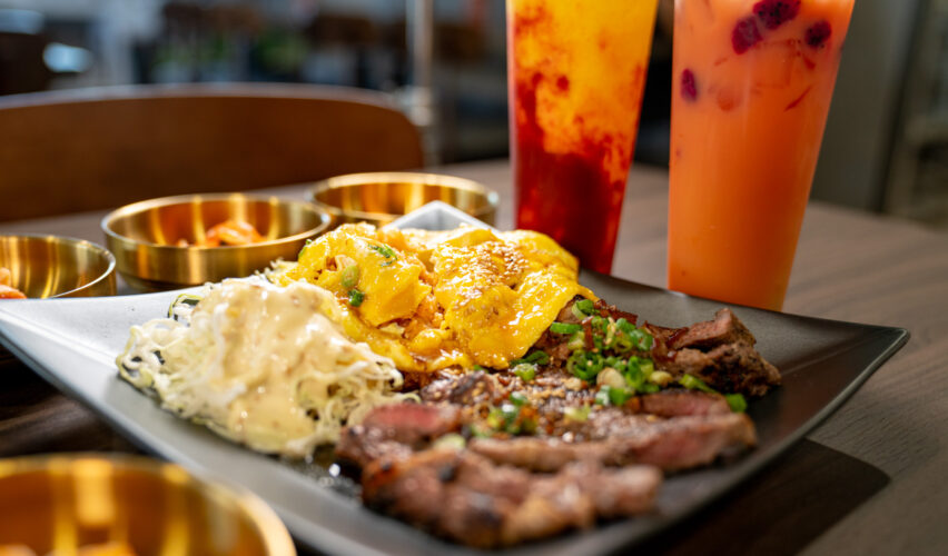 Food on plate top of table with two boba drinks on the side