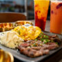 Food on plate top of table with two boba drinks on the side