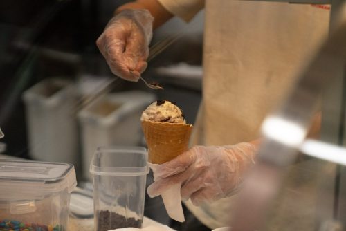 Adding chocolate chips to scooped ice cream in a cone 